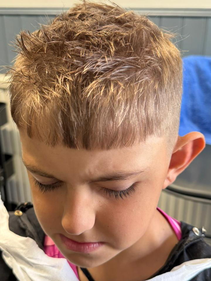 Front view of a boy's short haircut with a sharp, straight fringe/bangs cut.